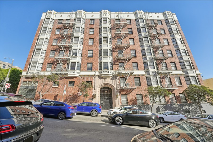 A tall apartment building with a parking lot in front of it.